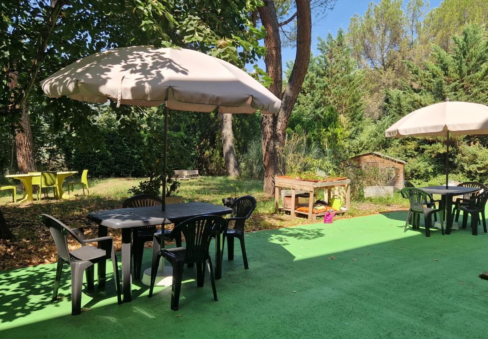 Terrasse arborée et parasols de la résidence Les Genêts